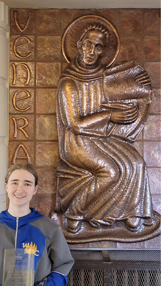 2024 Bede Award recipient Veronica Poquette with the copper frieze of the Venerable Bede.